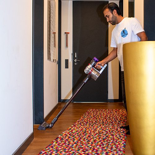 Ein Mitarbeiter von Sauber In Form saugt gründlich den Boden in einem modernen Innenraum.