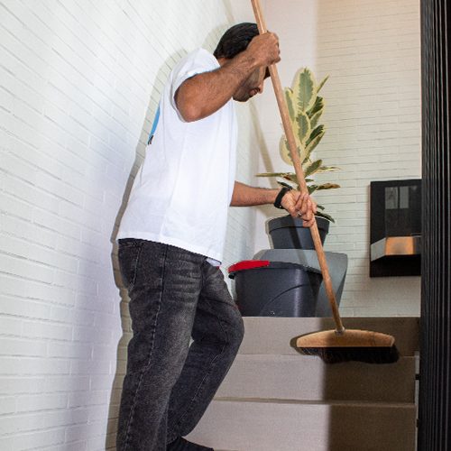 Ein Mitarbeiter von Sauber In Form kehrt die Treppen eines gepflegten Mehrfamilienhauses.