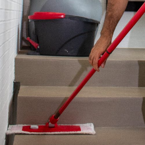 Ein Mitarbeiter von Sauber In Form reinigt die Treppenstufen sorgfältig mit einem Wischmopp.